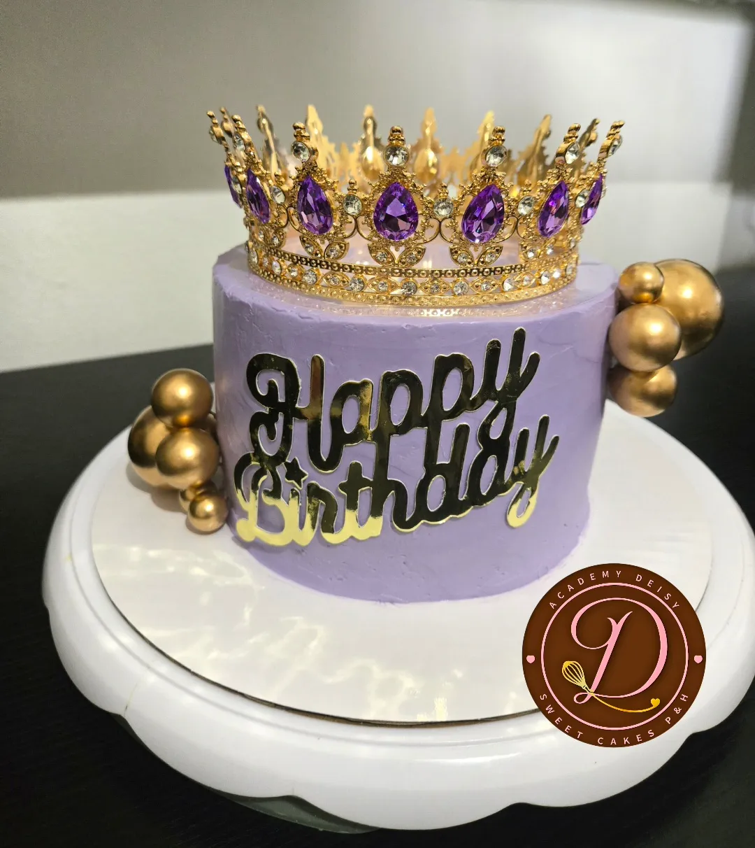 Cake lila con corona dorada y letras Happy Birthday en acrílico
